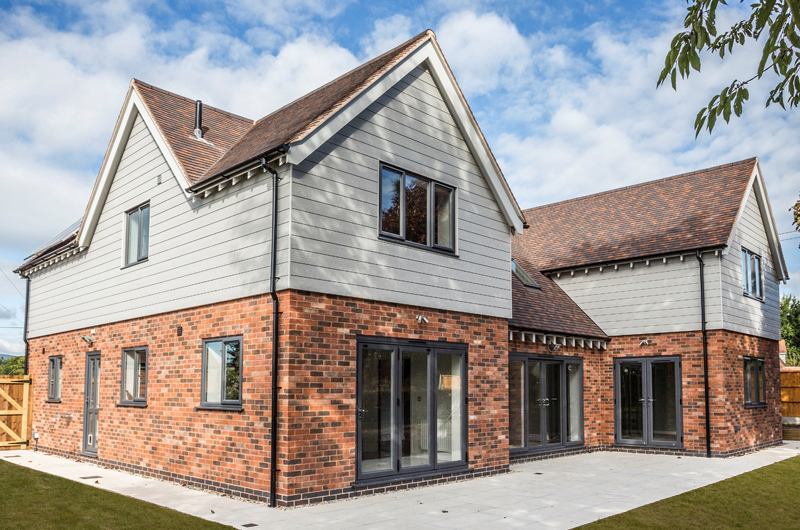 Modern two-story house with Cedral fibre cement facades and brown shingle roof, showcasing solutions for housebuilders