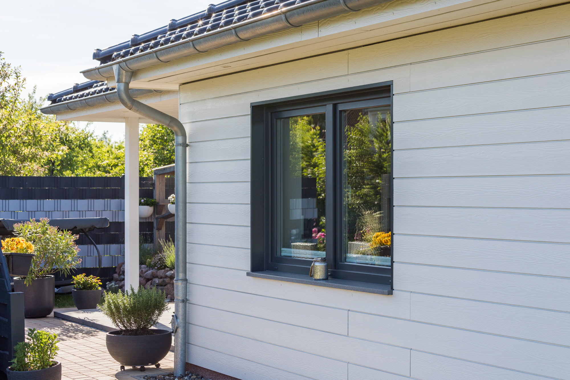 Close-up of white Cedral Lap fibre cement siding on a modern Canadian home with garden in the background.