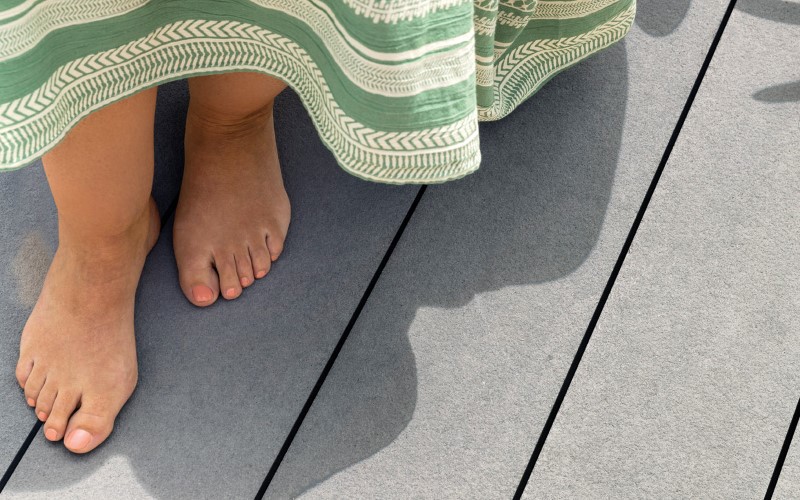 woman feet on a grey facade wearing white and green stripes dress