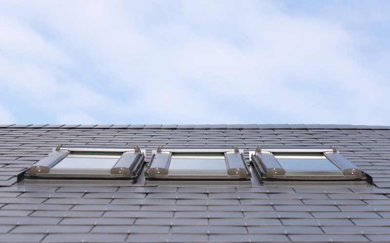 light blue slates on a roof with 3 windows in a middle and light blue sky above