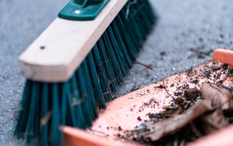 green broom is cleaning leafs from a roof 