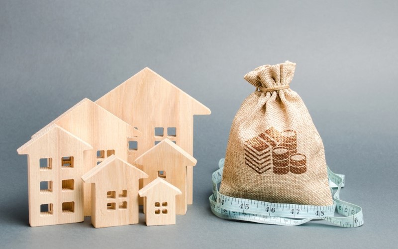 wooden houses and sand bag with a blue meter on a grey background