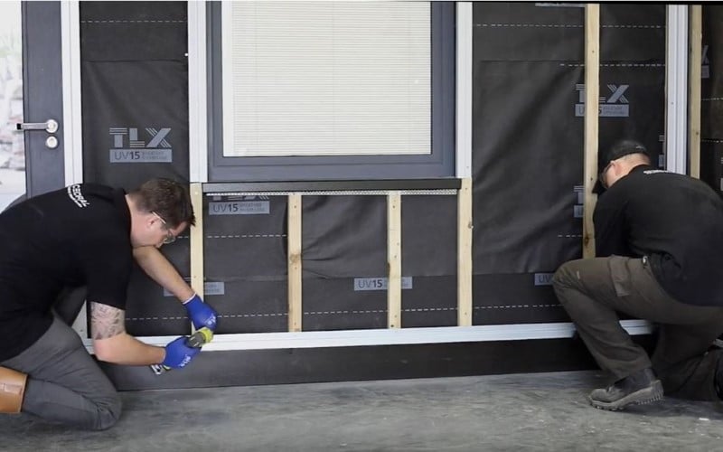 Cedral Lap weatherboards installation on a black house wall by two dressed black installers