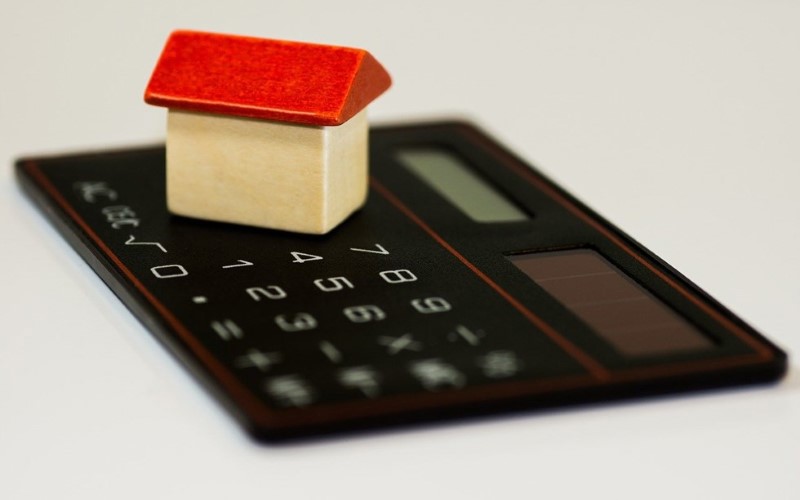 black calculator on it a house with red roof and sand colour siding