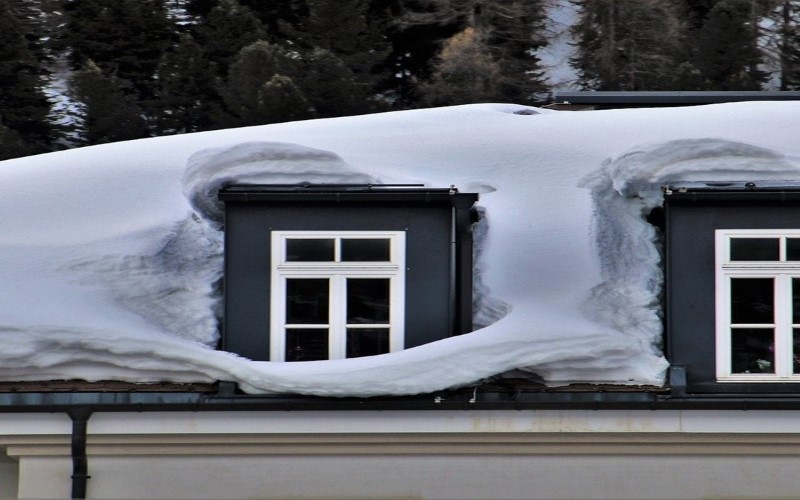 house roof with snow all over it with white frame windows