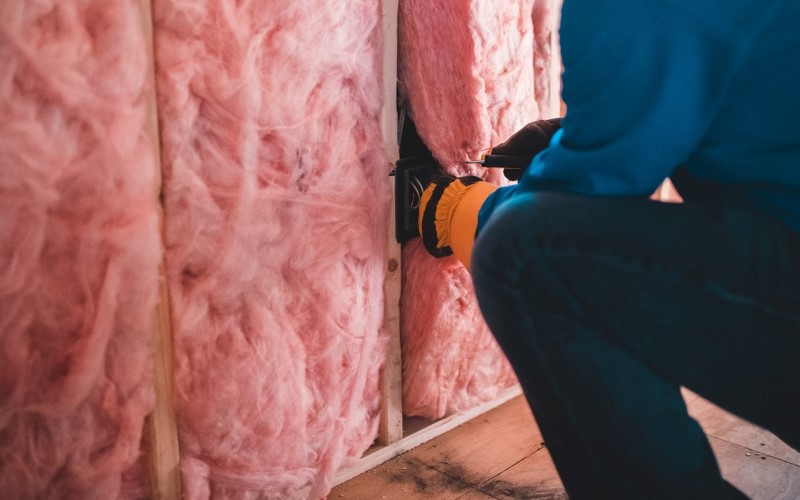 pink insulation being installed by an installer dressed blue