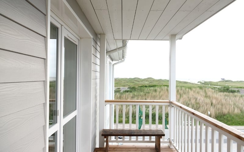 white facade white sky green hills and brown bench