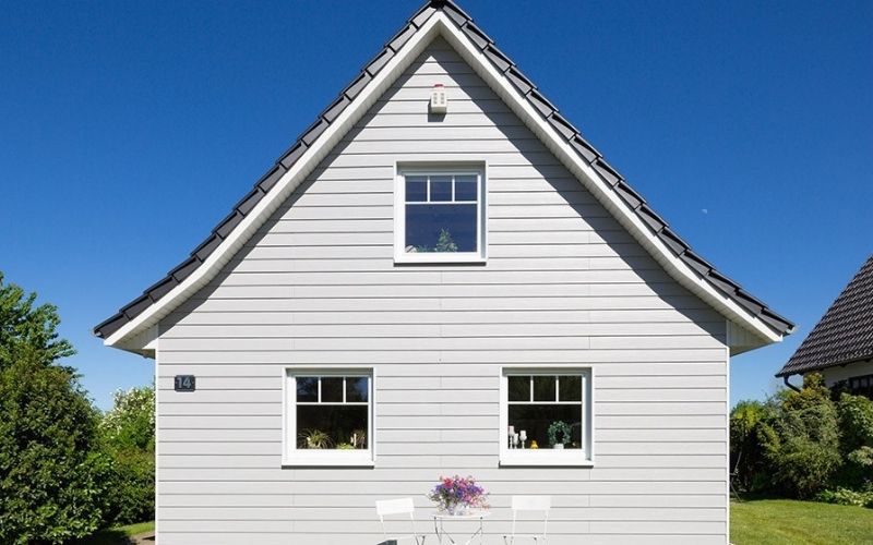 white weatherboards house blue sky green trees and grass