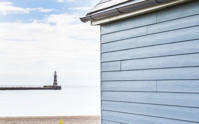 light blue weatherboards facade white sea blue sky and lighthouse