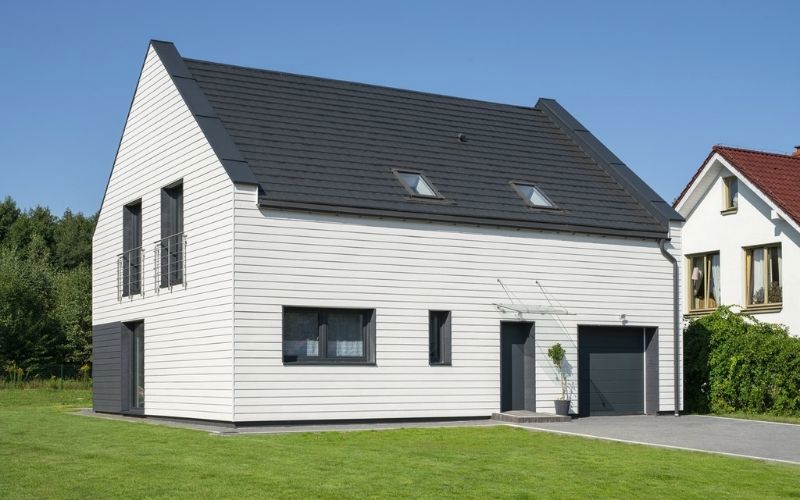 white siding house with grey slates on a roof and green grass below