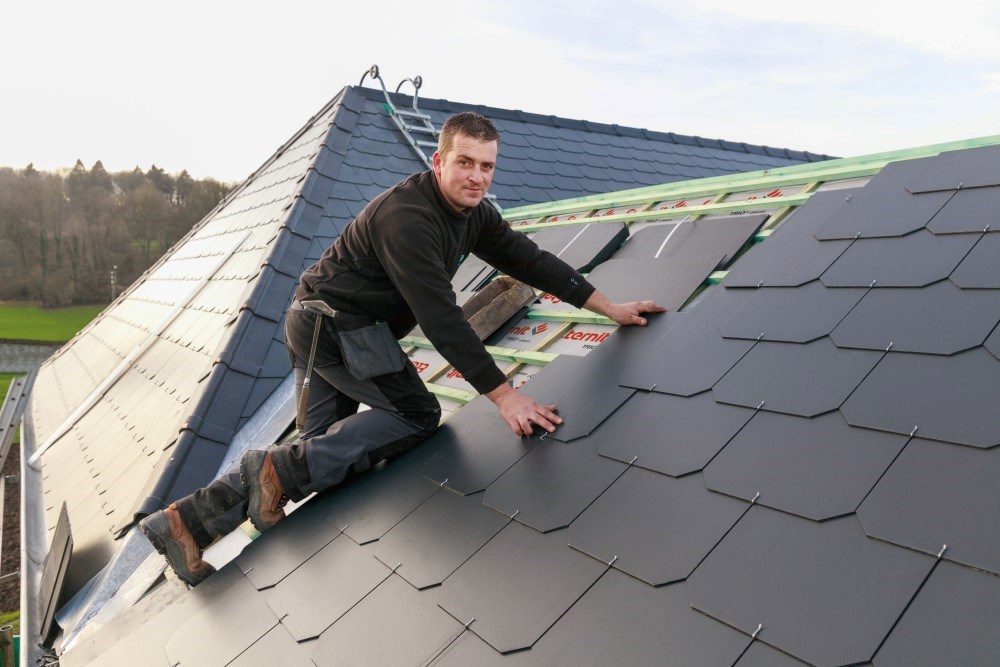 Roofer installing slates roof