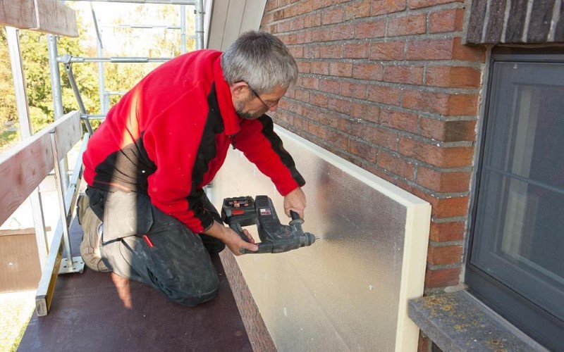 red dressed installer insulating the outside of the house