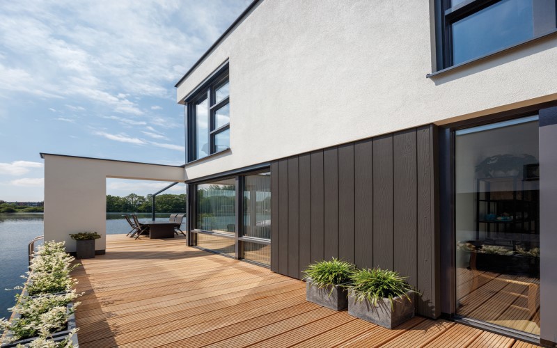 wooden house wall sidings brown and white on the left blue river and sky