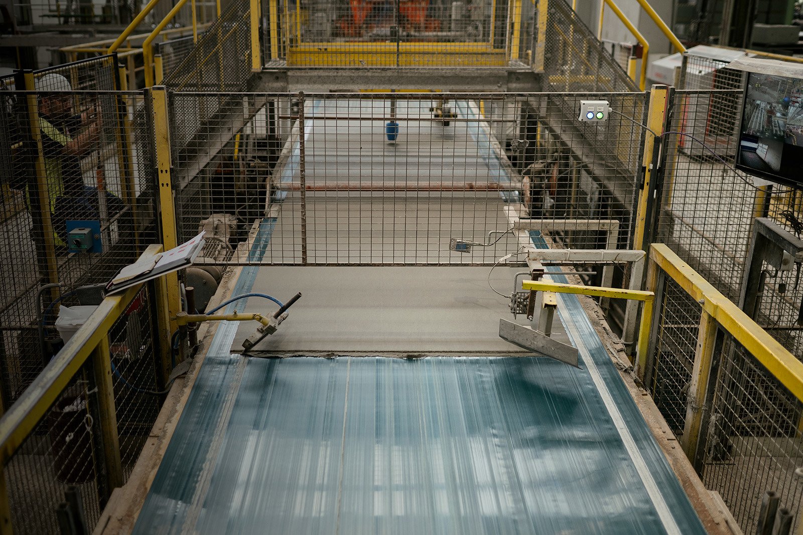 Industrial setting with Cedral fibre cement facade materials featuring a conveyor belt system and mechanical arms.
