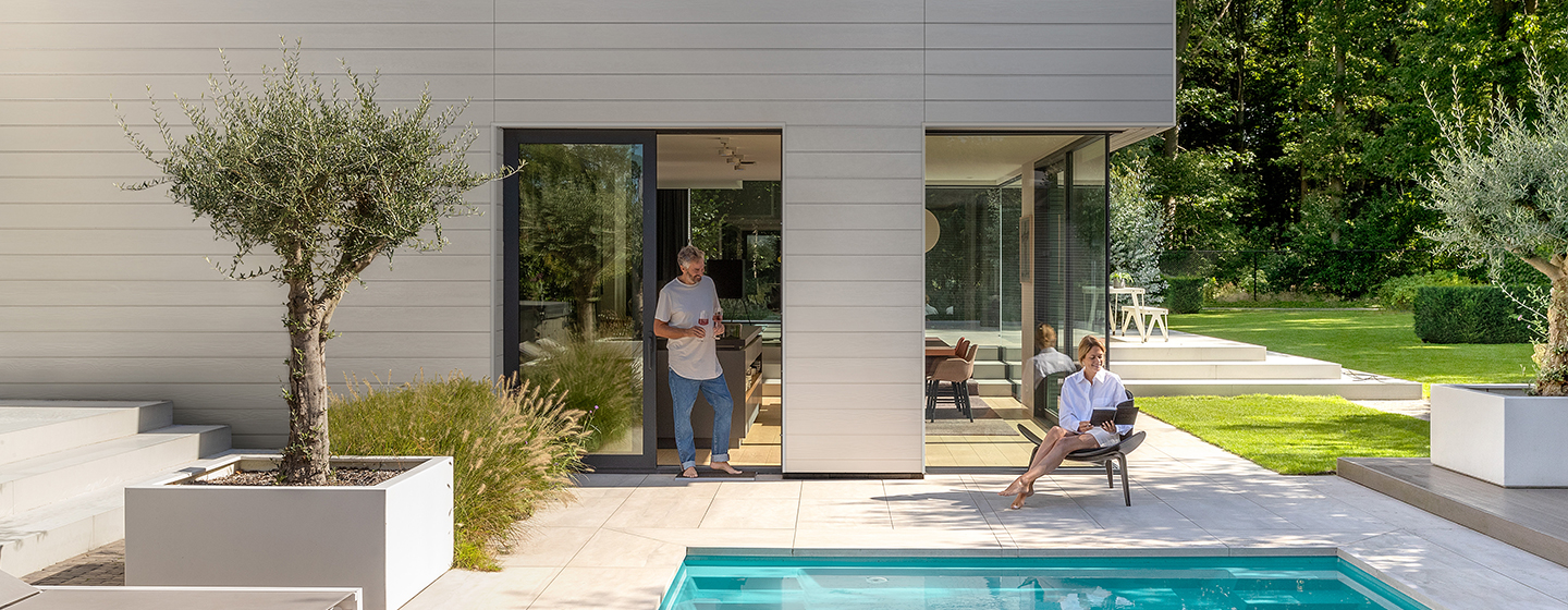 Grijze Cedral gevelbekleding tegen een moderne woning met zwembad