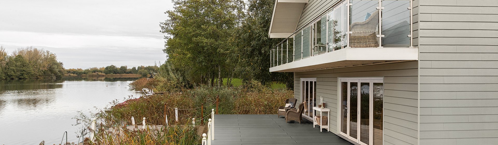 Moderne Gebäudefassade mit horizontal verlegten Paneelen in dezentem Grauton, glatte Oberfläche, klare Linienführung und harmonisches Gesamtbild.