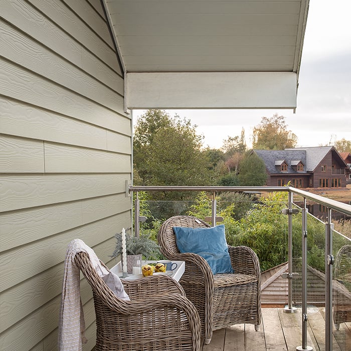 Moderne Gebäudefassade mit horizontal verlegten Paneelen in dezentem Grauton, glatte Oberfläche, klare Linienführung und harmonisches Gesamtbild.