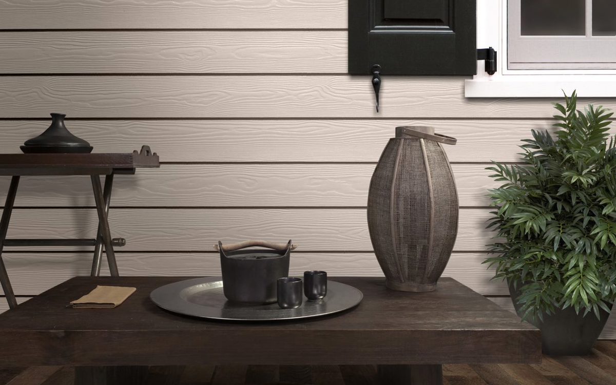 brown table on top of it silver plate and black cups behind it light sidings on the right green plant above it black window
