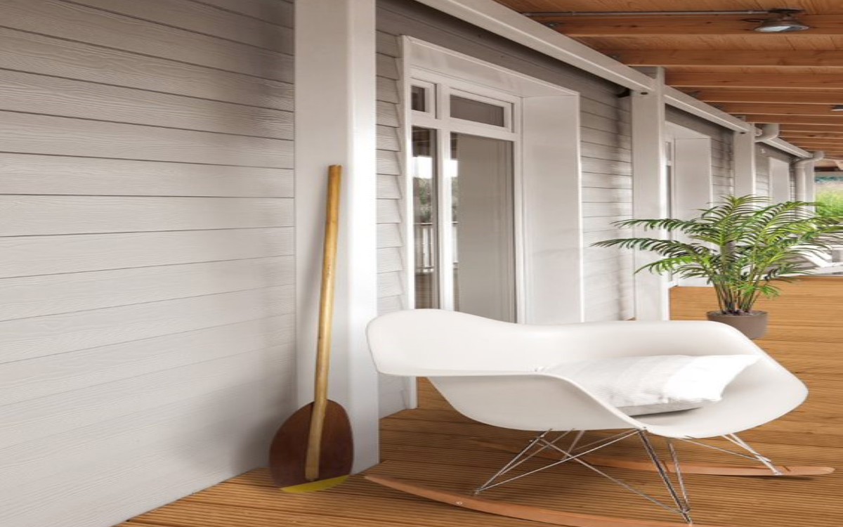 on the left light sidings in the middle white armchair behind it green plant the ground is wooden